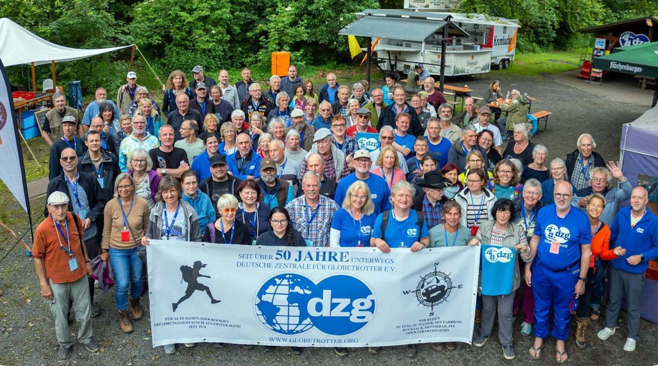 Menschengruppe hinter einem Banner 50 Jahre dzg